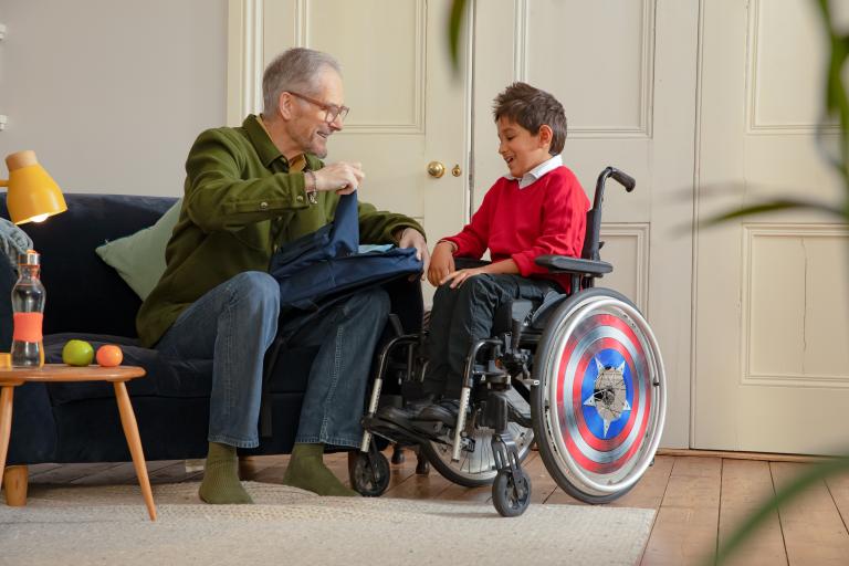 An elderly gentleman chatting to a young boy in a wheelchair