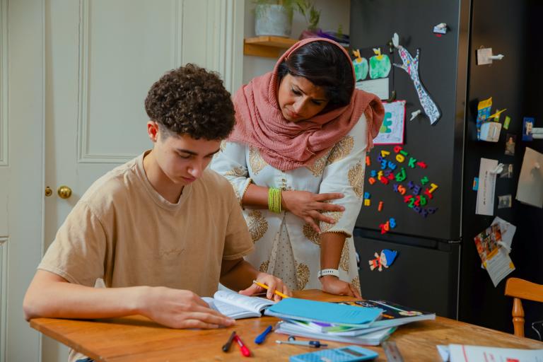 Lady helping a teenage boy with his homework